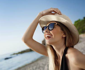 Pessoa se protegendo do sol com óculos escuros com proteção UV e chapéu